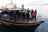 a group of people stand at the front of a boat talking