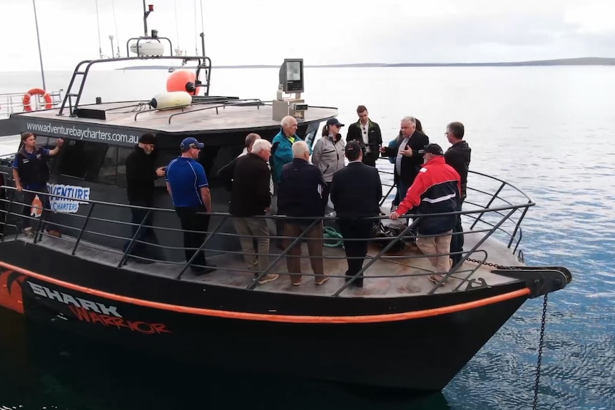 un grupo de personas se paran en la parte delantera de un barco hablando