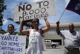 Demonstrators hold up placards protesting the presence of US troops in Guam.