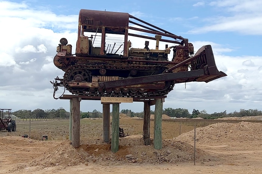 An old rusted out bulldozer on top of shortened power poles