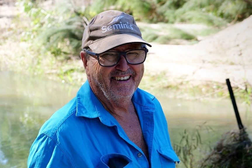 a man smiling in a blue work shirt