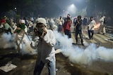 Muslim hardline protesters cover their faces as police fire tear gas