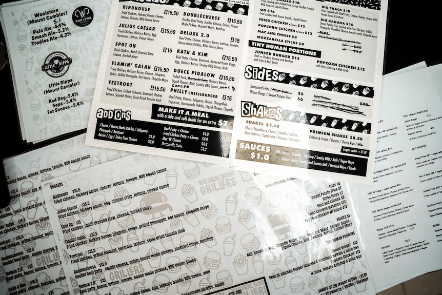 Two black and white menus with burger items on a cafe table.