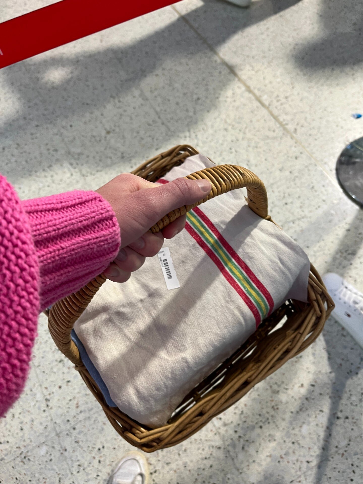 A hand holding a basket with a cake wrapped in a teatowel.