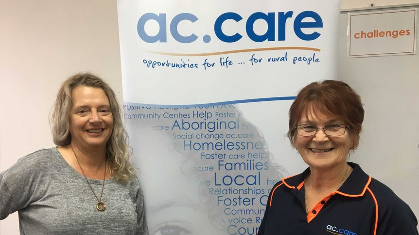 Two women standing in front of AC Care banner.