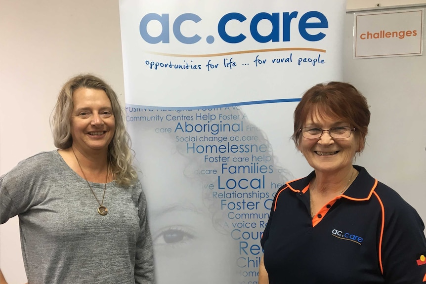 Two women standing in front of AC Care banner.