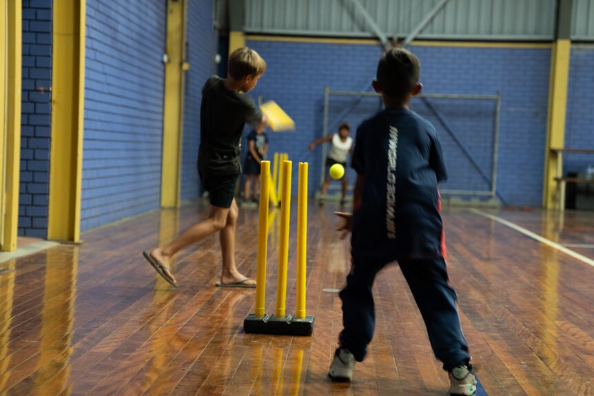Two young Indigenous boys play indoor cricket
