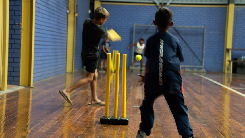 Two young Indigenous boys play indoor cricket
