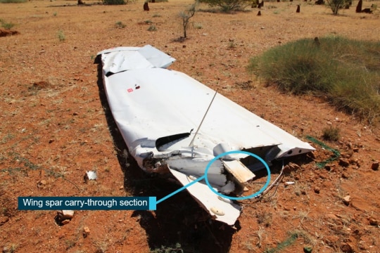 a plane wing on dirt ground