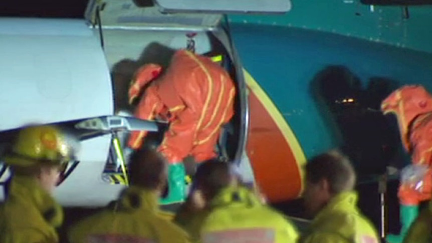 Authorities in protective suits check a cargo plane in Hobart after a white powder was discovered.
