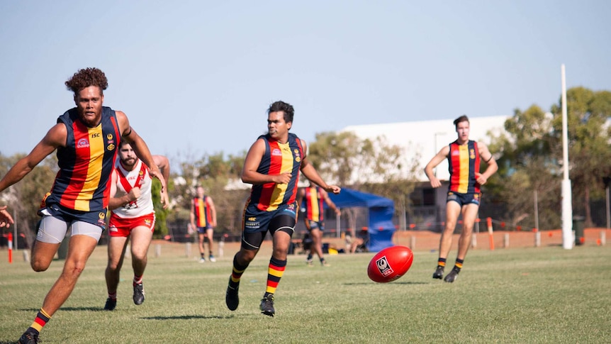 Footballers chasing after the ball during a Grand Final contest in Broome in 2019.
