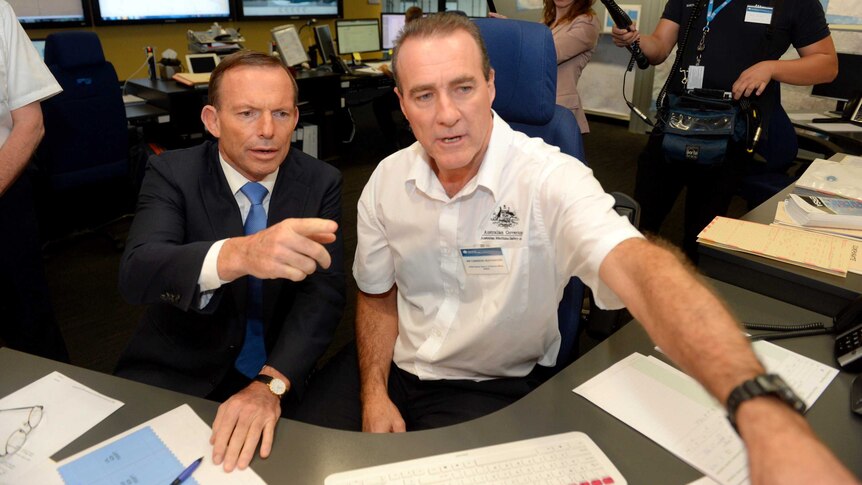 Prime Minister Tony Abbott listens to AMSA search and rescue officer Cameron Heathwood.