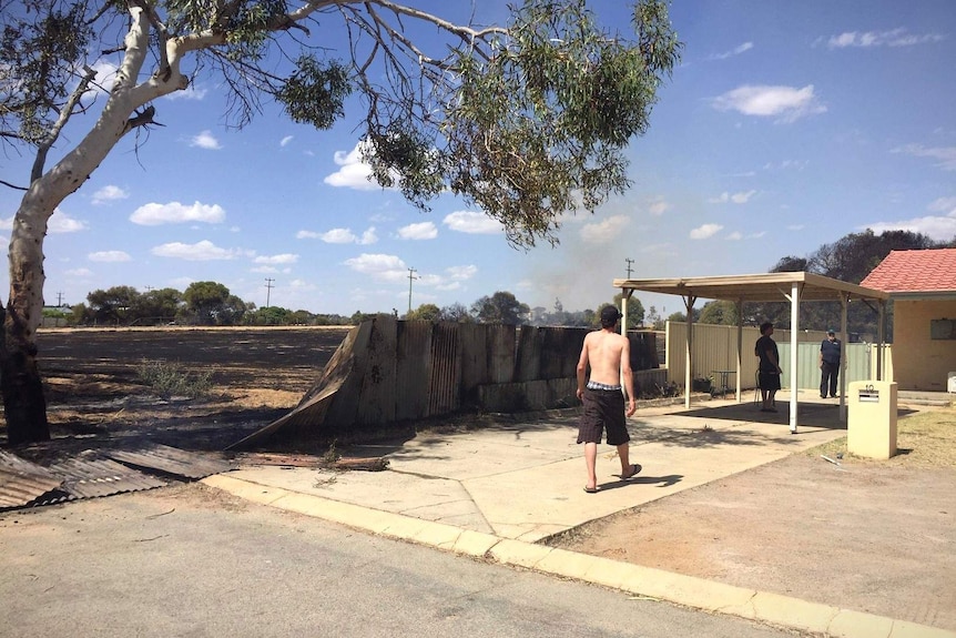 A smouldering fence divides charred bushland and a residential home