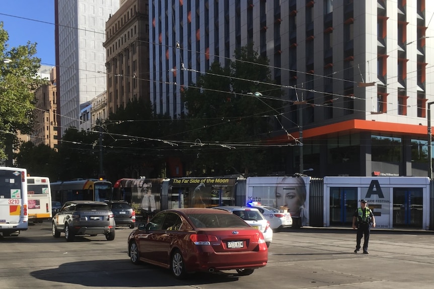 Buses and cars are directed around a stationary tram.