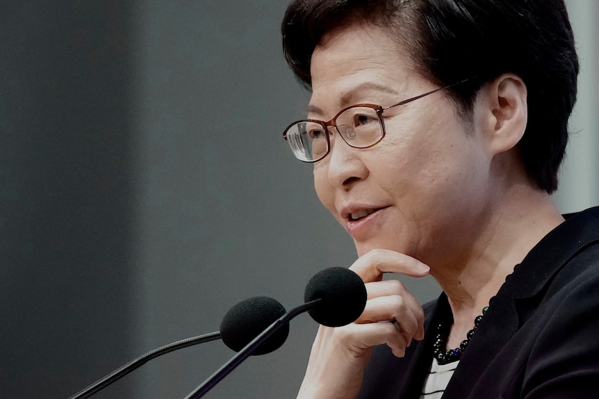 Hong Kong leader Carrie Lam smirks as she speaks into microphones