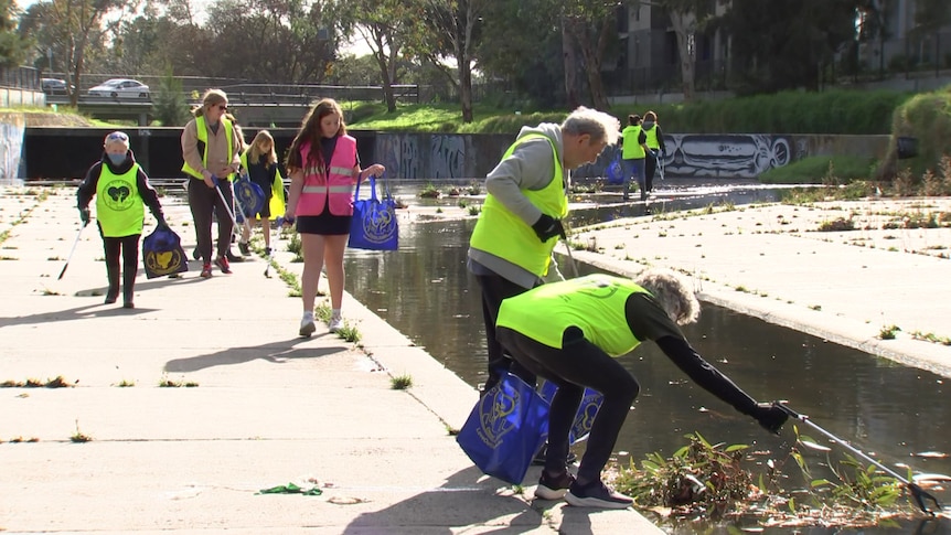 People clearing a canal of litter