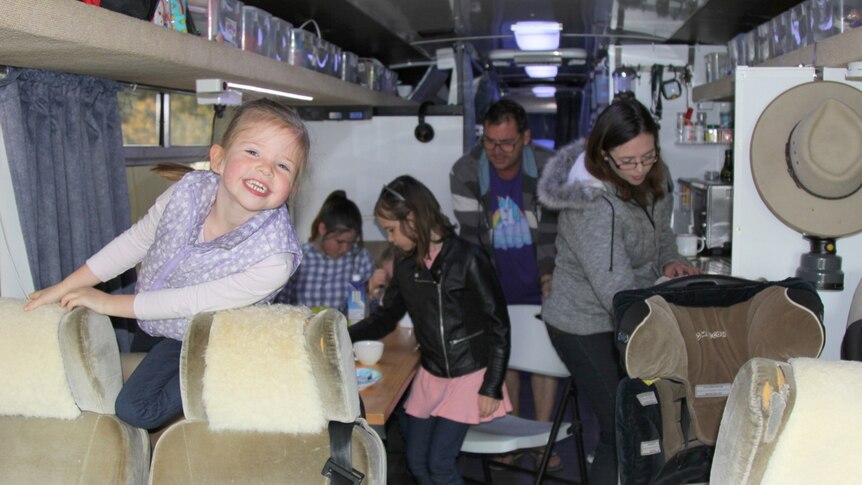Family inside bus fitted with a kitchenette.
