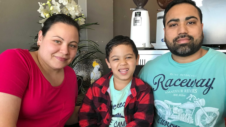 Mother, father and five year old boy in the middle smiling for the camera