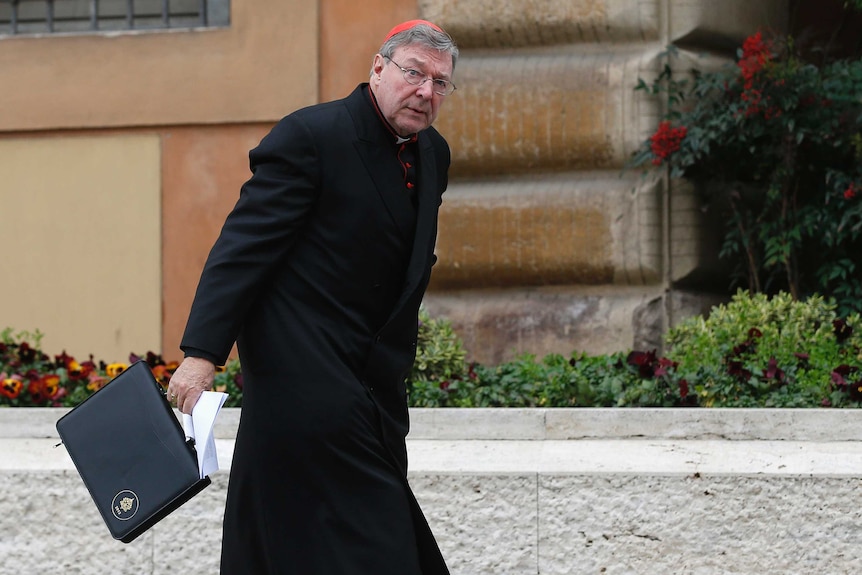 George Pell carries a briefcase as he arrives for a meeting