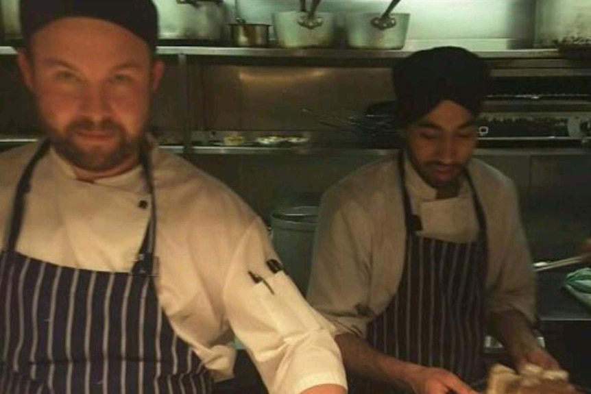 Brisbane chef David Carter chef in apron looking at camera holding a sauce bottle.