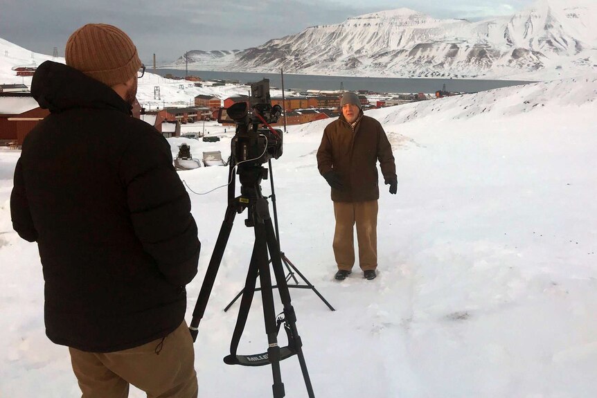 Steven Schubert filming man in beanie and coat with snow covered mountain in background.