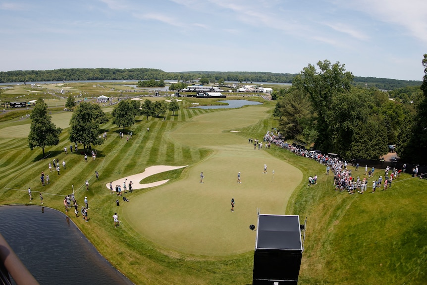 An aerial view of a lush-looking golf course dotted with people.