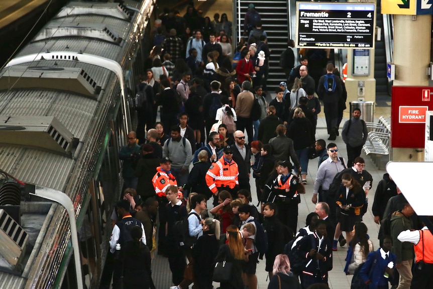 A crowd moves on and off a train at Perth Station from the Fremantle Line as transit guards stand by