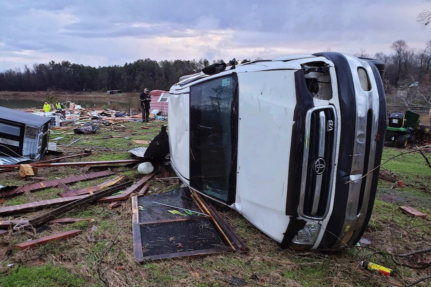 An overturned ute sits among rubble after a severe storm.