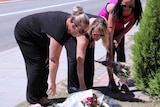 A group of women lay flowers on a footpath in Canning Vale after the death of a teenager hit by a car.