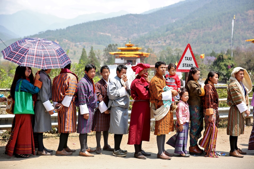 Les gens font la queue en costume traditionnel du Bhoutan.
