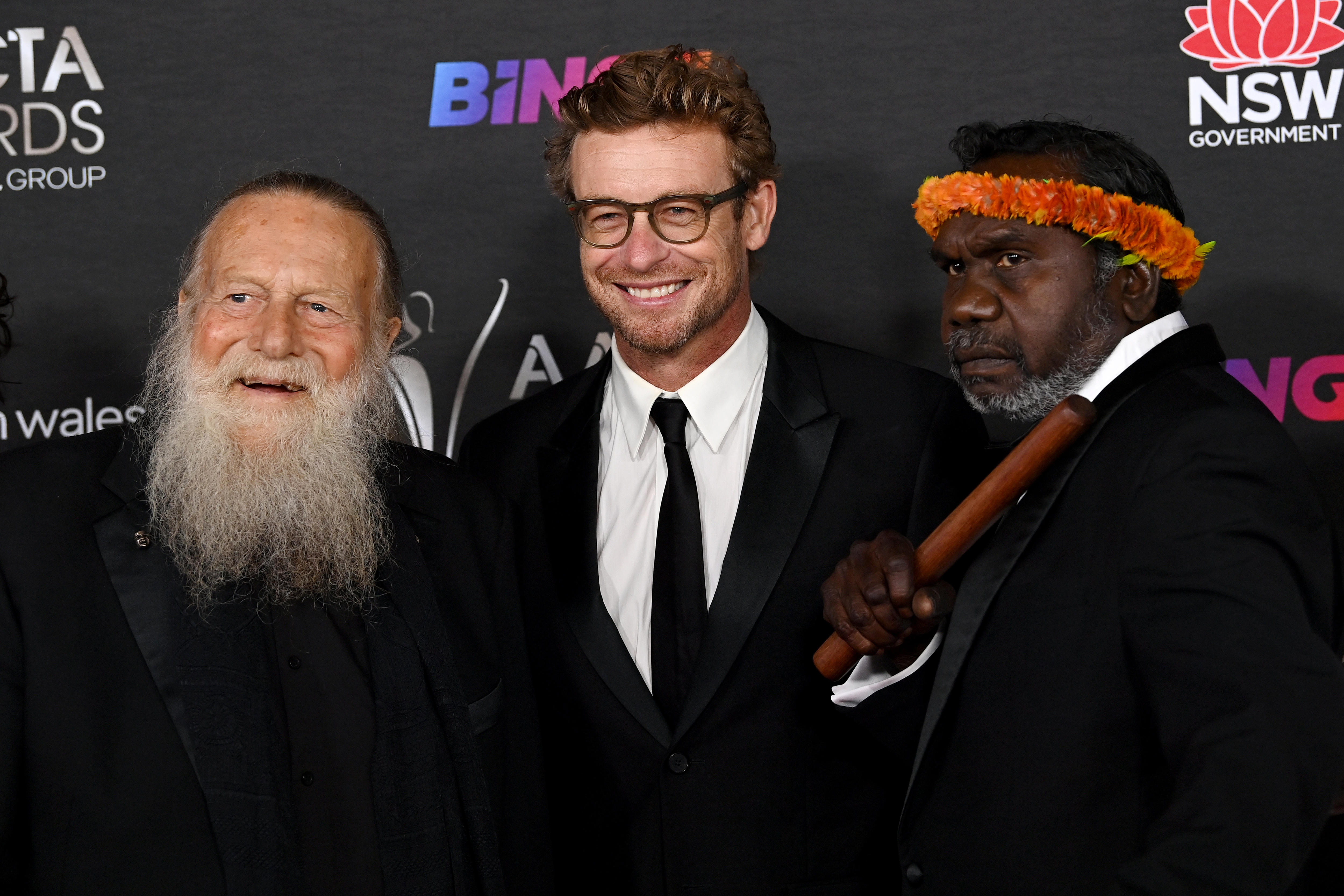 Jack Thompson, an older man with a long white beard with Simon Baker and Witiyana Marika who wears an orange headdress