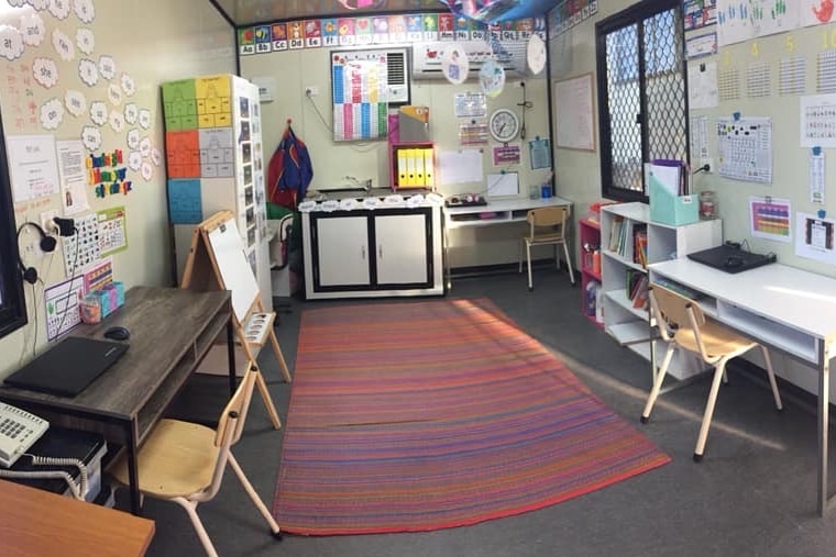 A home school room with lots of colourful charts on the walls lined by children's desks
