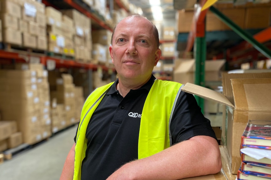 Man stands in high vis vest in warehouse in QBD polo 