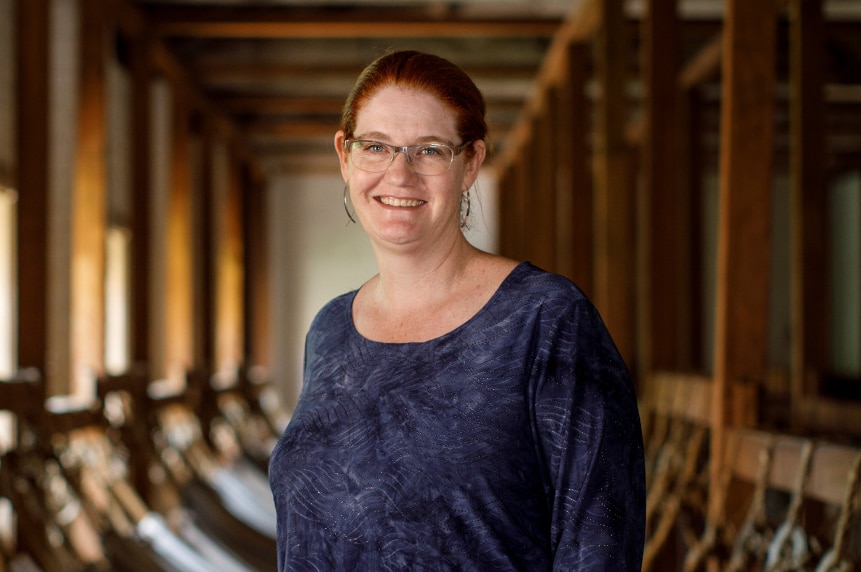 A woman stands in a hammock room smiling at the camera