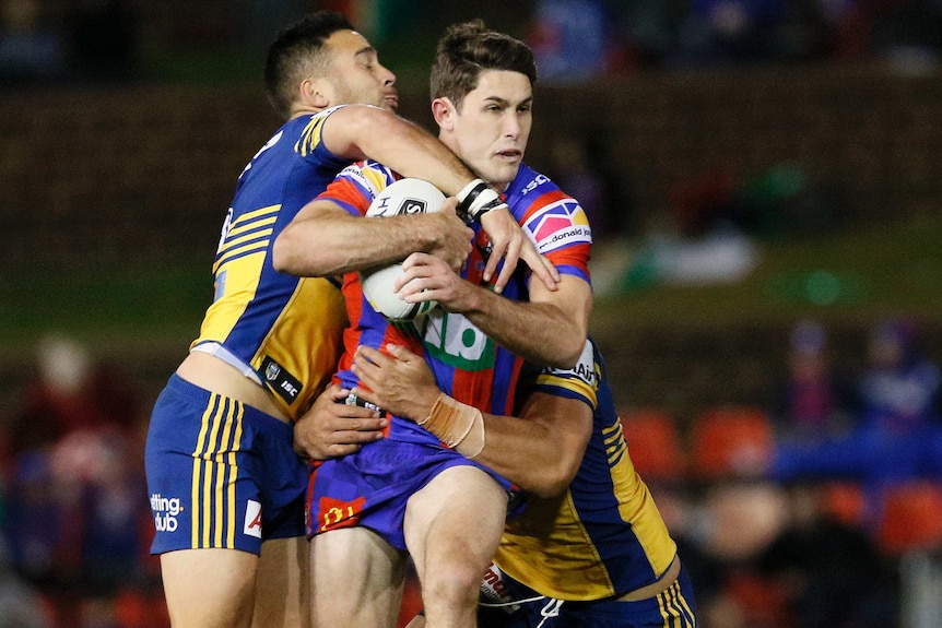 Nicholas Meaney of the Knights is tackled by the Eels.