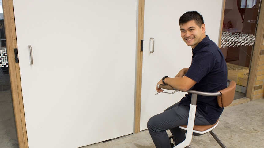 A man sits on the seat of a white walking frame