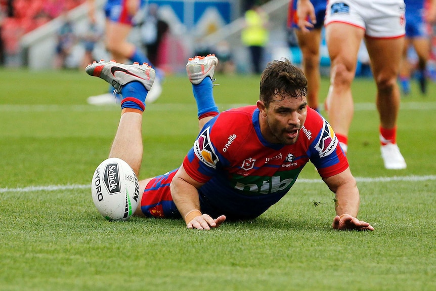 A Newcastle Knights NRL players slides on his stomach after socring a try against St George Illawarra.