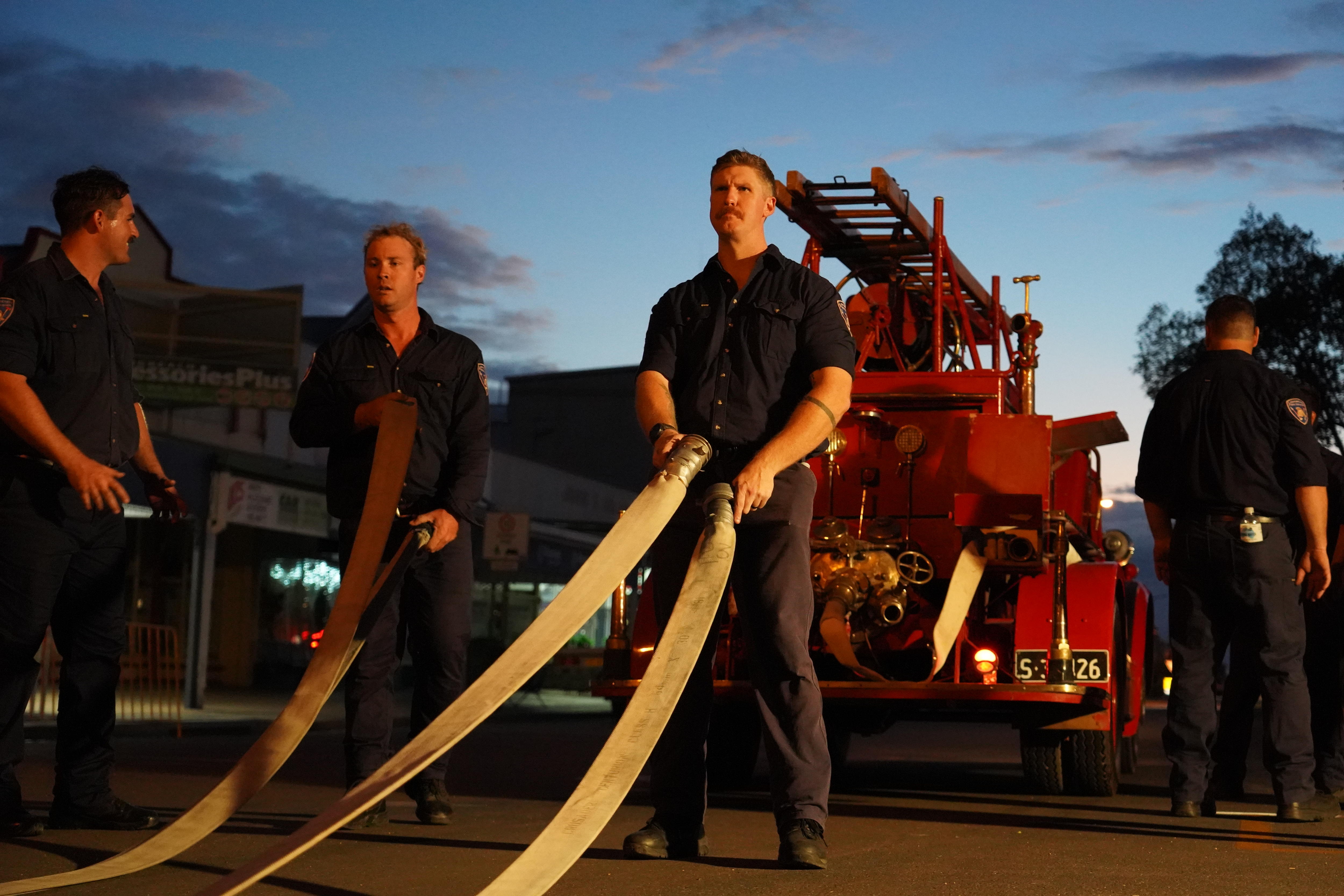 Strong firefighter holding hose, truck behind him