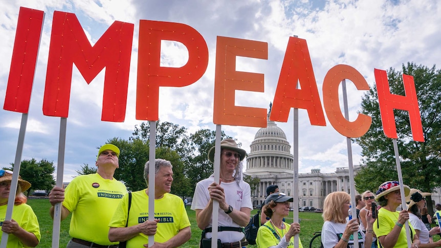 Activists rally for the impeachment of President Donald Trump, while holding the letter to the word Impeach.
