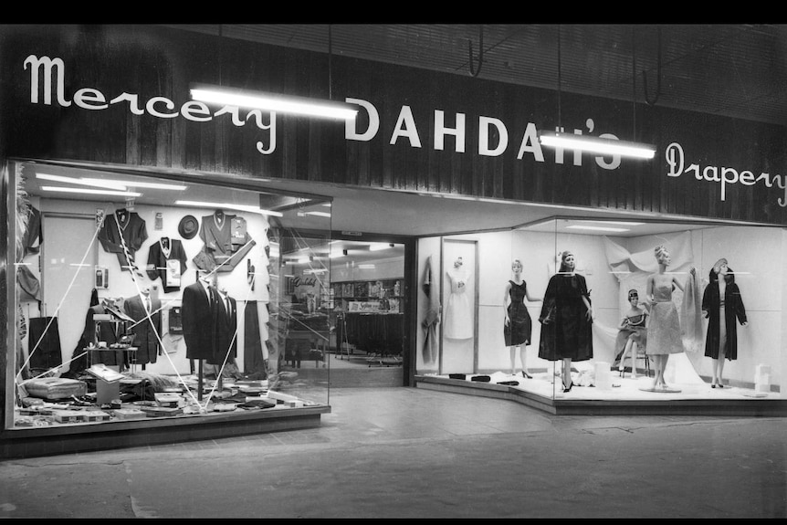 A black and white photo showing a clothing store shop window, called Dahdah's.