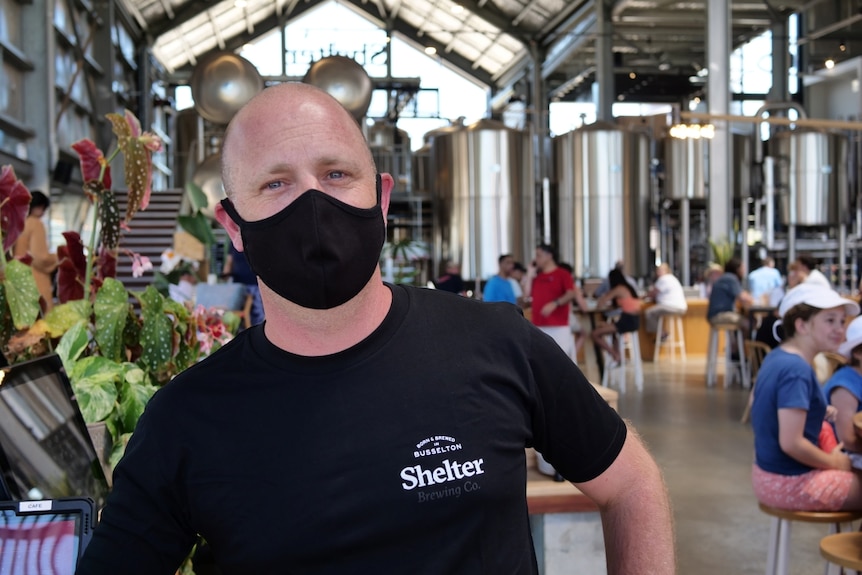 A man with a face mask stands in a restaurant