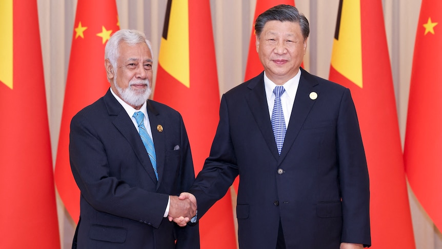 Xi Jinping shaking hands with Xanana Gusmao in front of Chinese flags. 