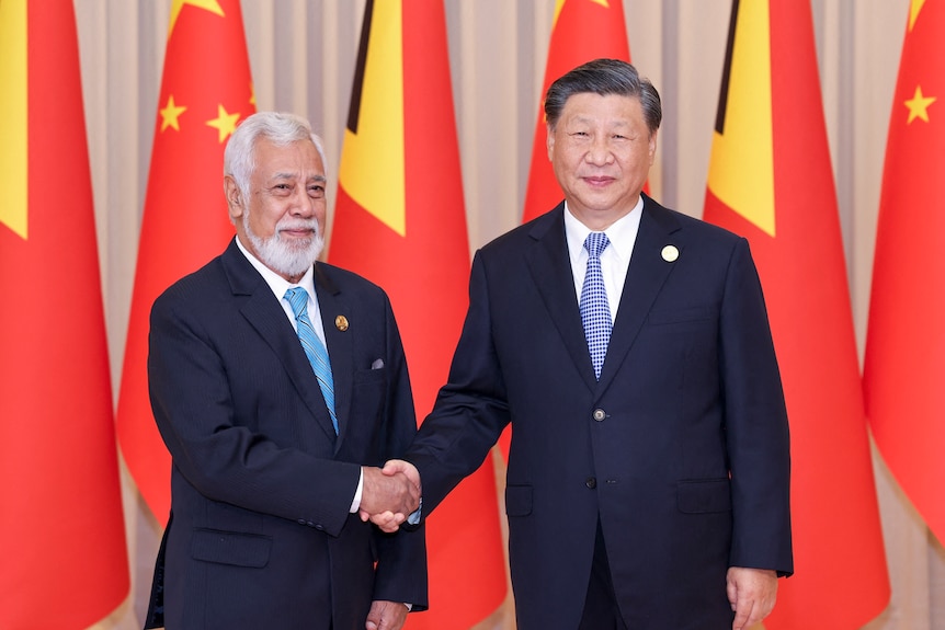 Xi Jinping shaking hands with Xanana Gusmao in front of Chinese flags. 