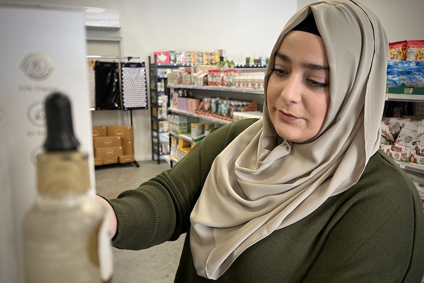 Betul stacking shelves in her Coolaroo store in September 2022 in interview with Nassim Khadem