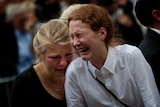 Women react in Oslo at the end of a memorial service 