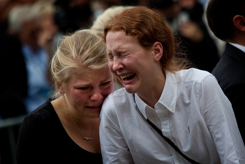 Women react in Oslo at the end of a memorial service 