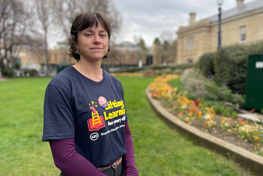 A woman wearing a slogan t-shirt looks at the camera.