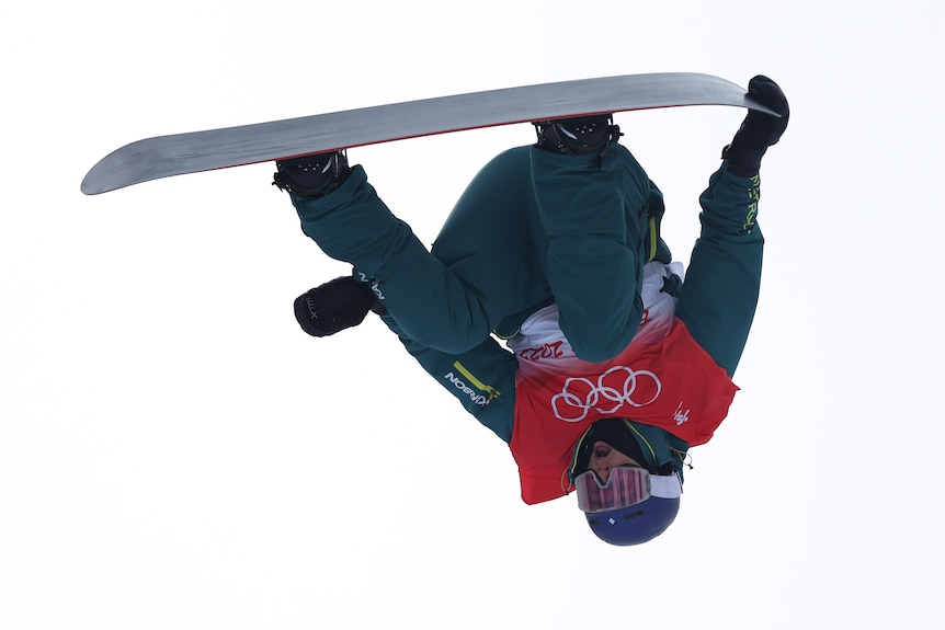 An Australian male snowboarder in the air during the halfpipe qualification event at the Beijing Winter Olympics.