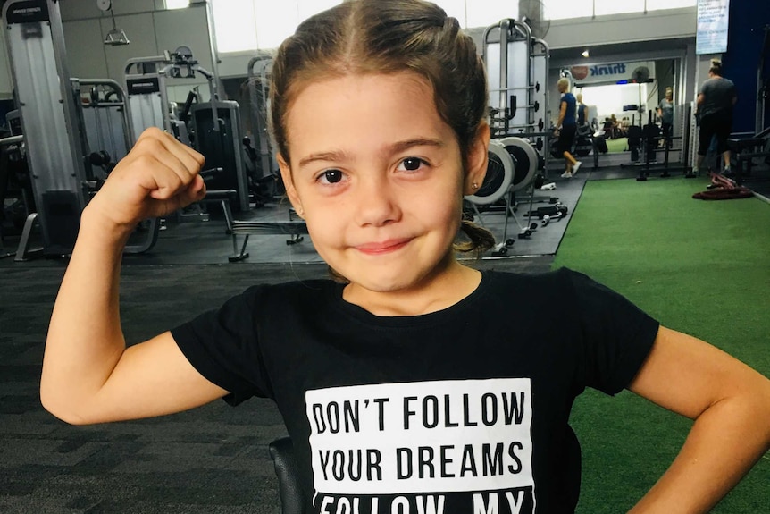 Wheelchair athlete Brydi Saul, nine, poses for the camera in a gym.