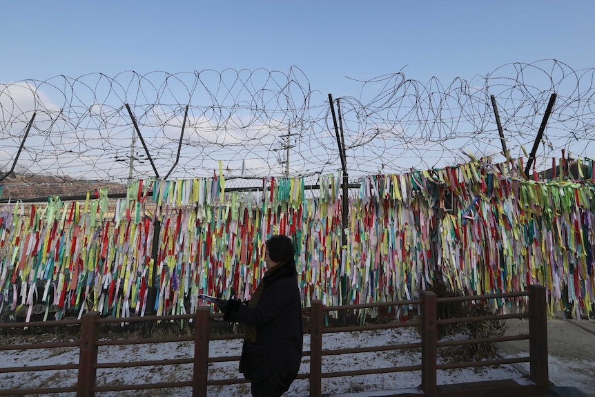 A visitor walks by the wire fence decorated with ribbons carrying messages to wish for the reunification of the two Koreas